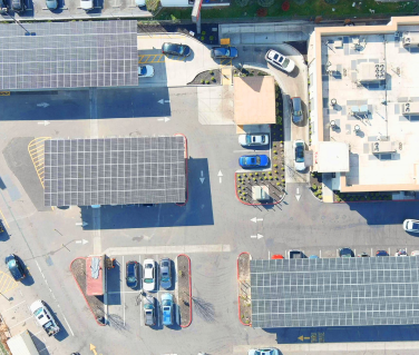 Aerial view of a parking lot with solar panel structures and a building.