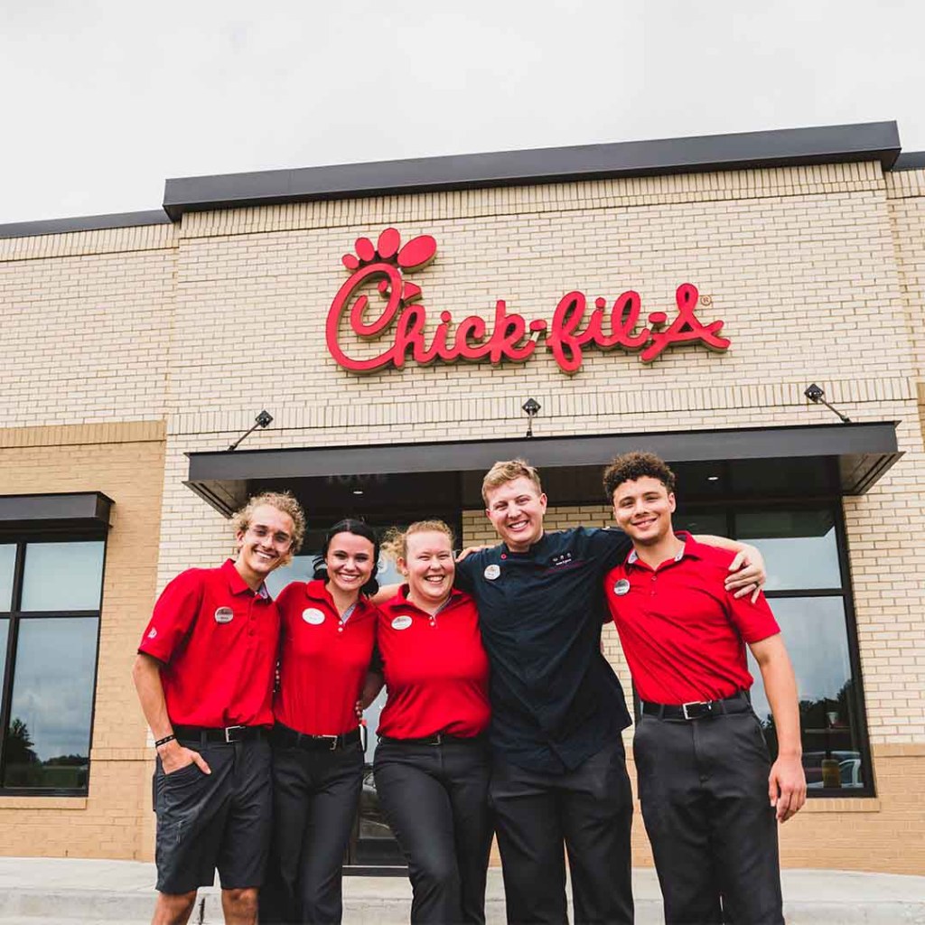 A group of Team Members standing outside a Chick-fil-A Restaurant with their arms around each other