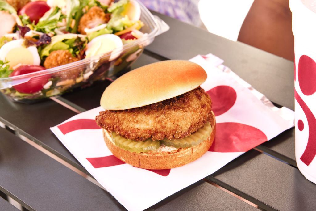 Chick-fil-A® Chicken Sandwich on a picnic table, displayed on a Chick-fil-A takeout bag