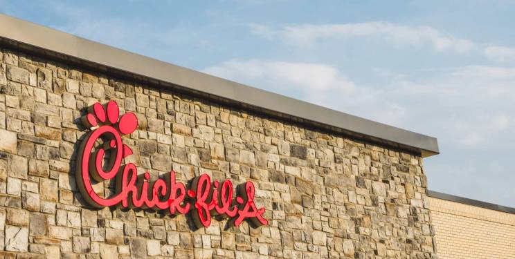 Building wall with stone facade and red Chick-fil-A logo.