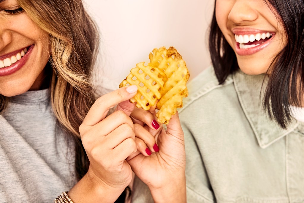 Two smiling ladies cheersing with Chick-fil-A waffle potato fries