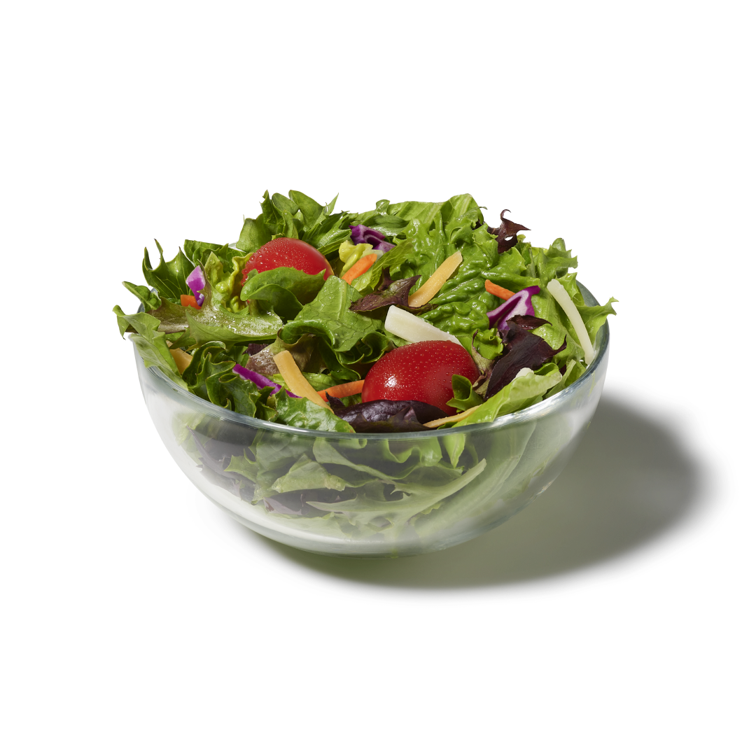 Side salad featuring a bed of mixed greens topped with shredded Colby Jack cheese and grape tomatoes in a transparent bowl. 